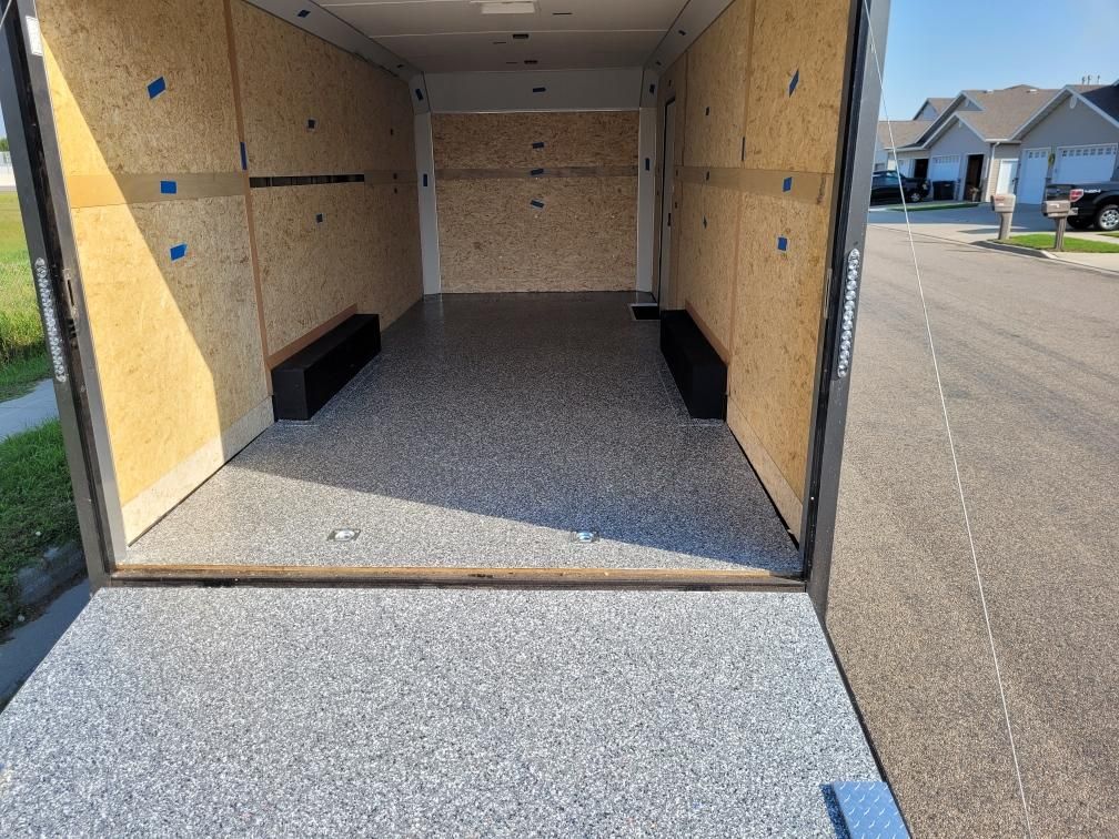 The inside of a trailer with a gray floor and wooden walls.