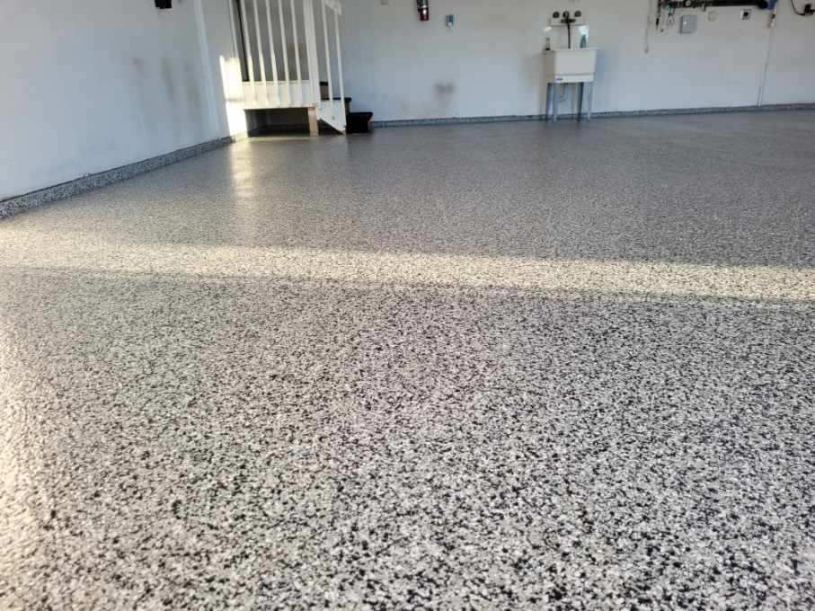 A garage floor with a sink and stairs in the background.