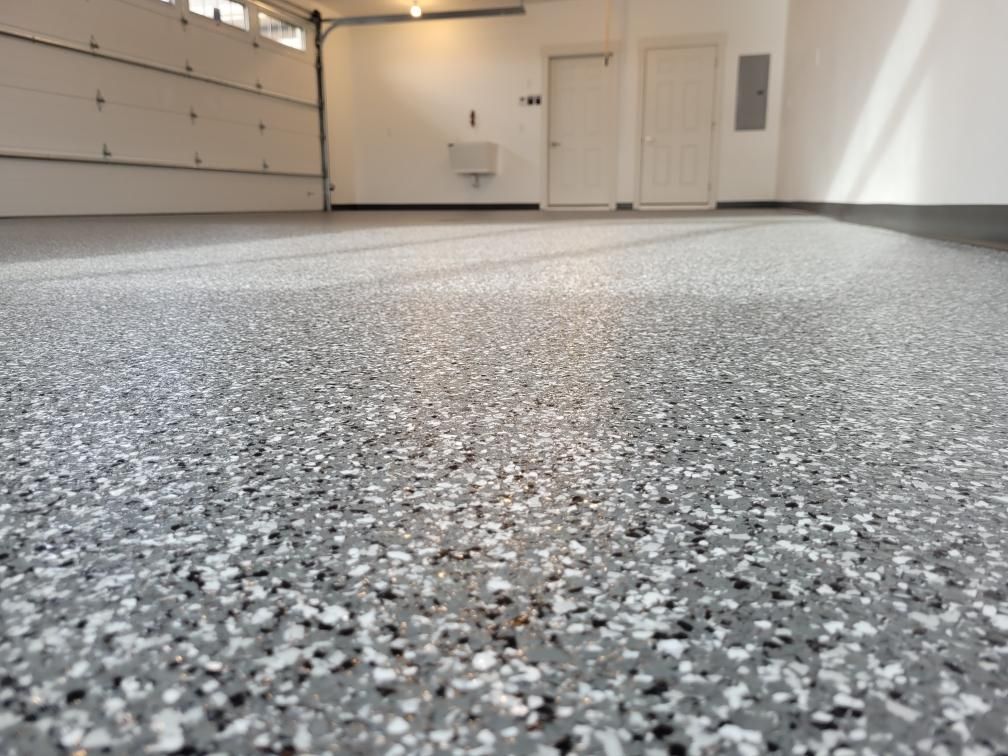 A garage with a gray and white floor and a garage door.