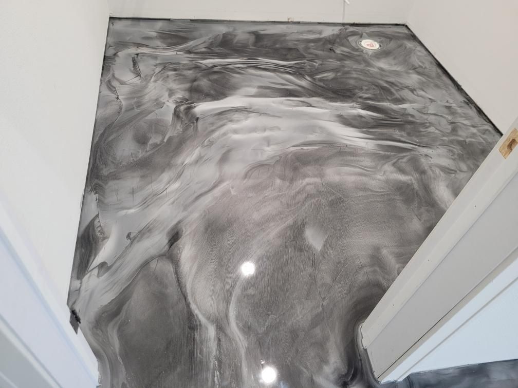 A gray and white marble floor in a hallway next to a door.