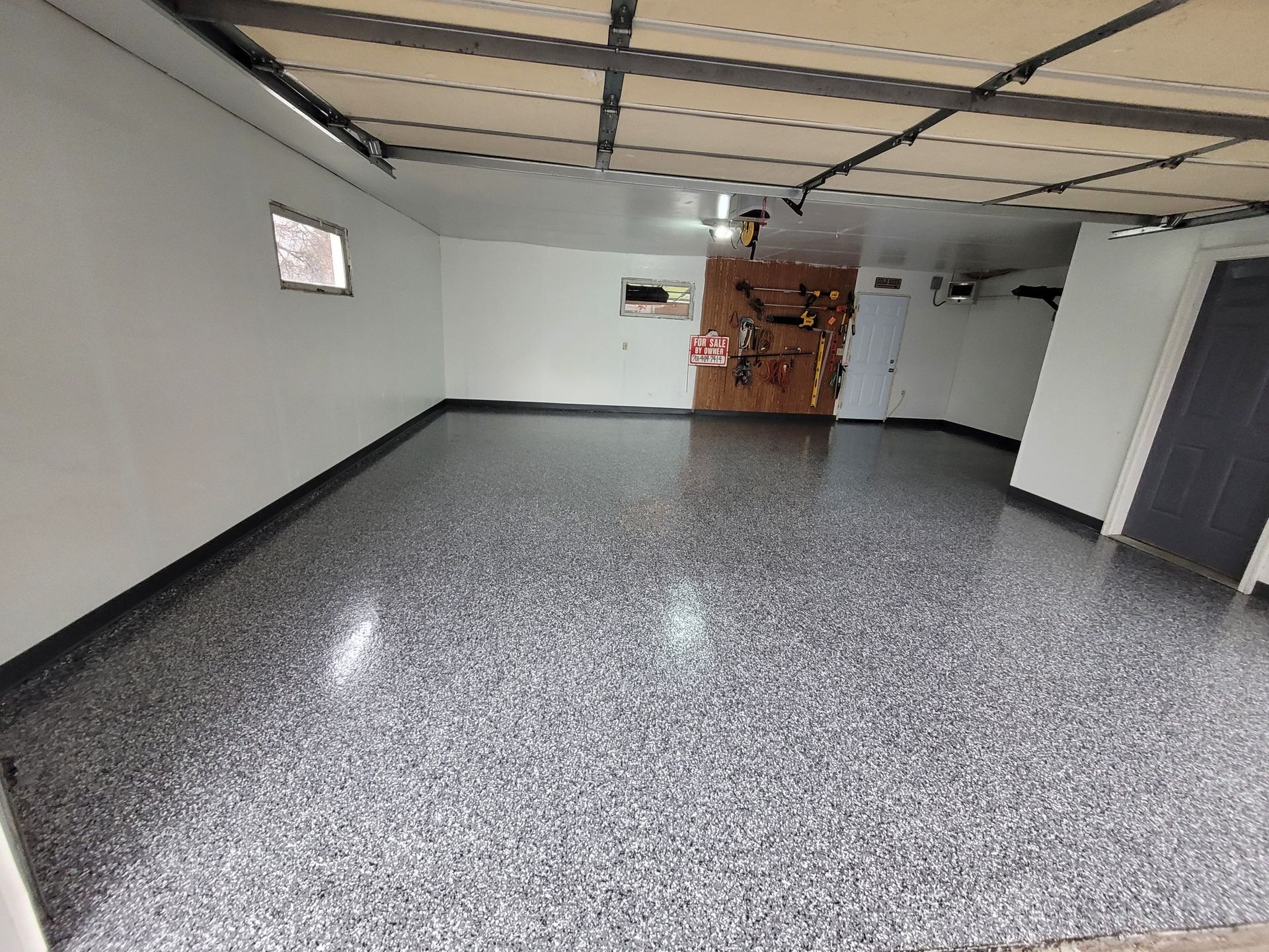 A large empty garage with a gray floor and white walls.