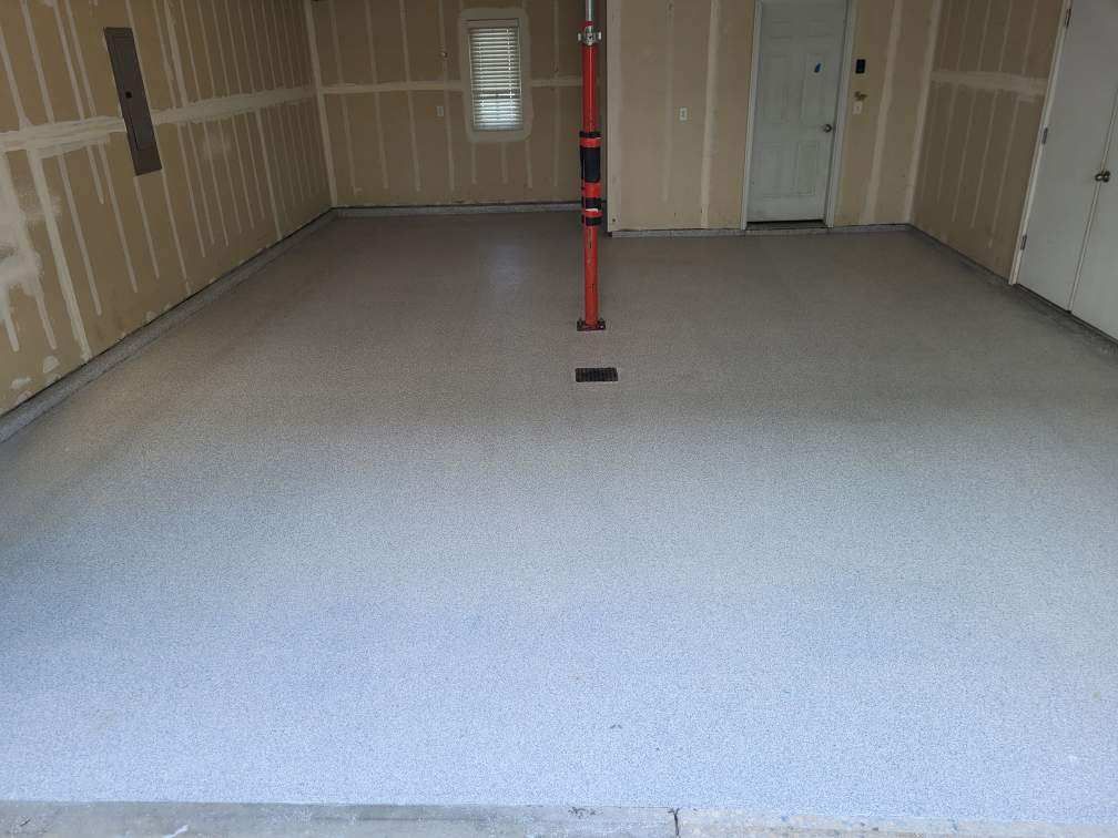 A garage with a concrete floor and a red pole in the middle.