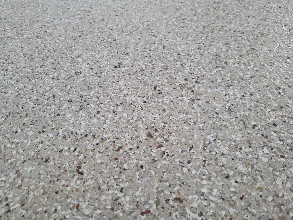 A close up of a concrete floor with a lot of small stones on it.