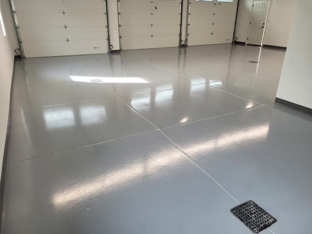 A garage with a gray floor and white garage doors.