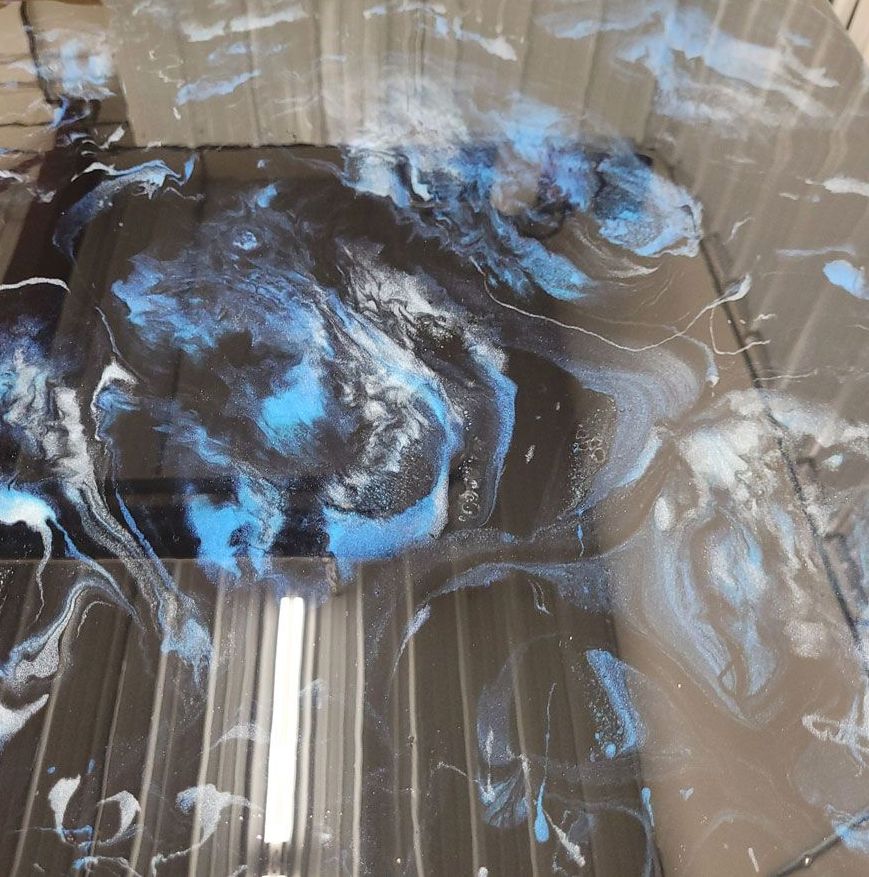 A black and blue painting on a metal surface