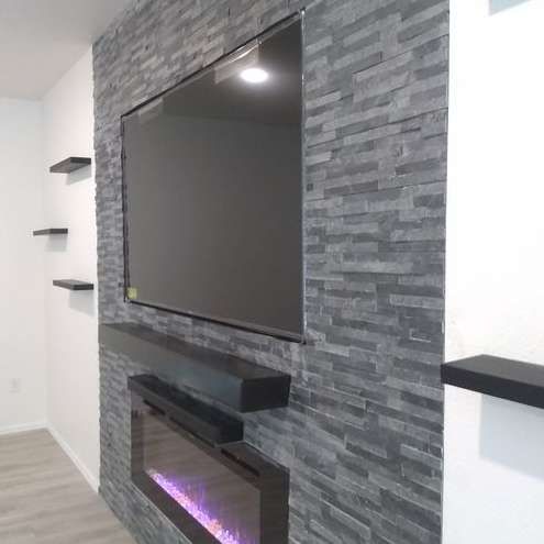 A living room with a fireplace and a flat screen tv mounted on the wall.