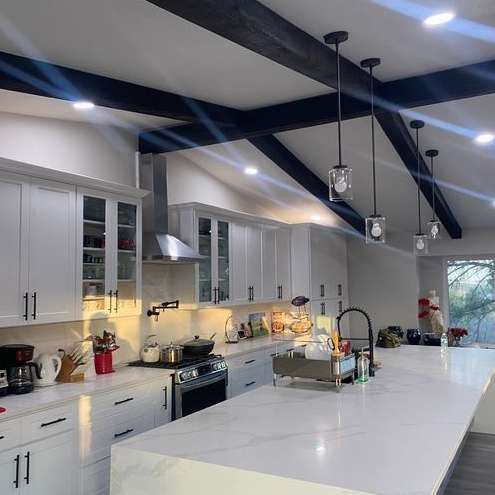 A kitchen with white cabinets , a stove , a sink , and a large island.
