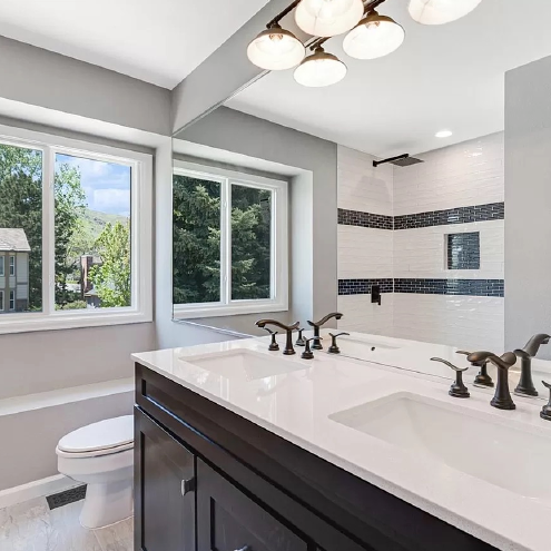 A bathroom with two sinks , a toilet , and a large mirror.