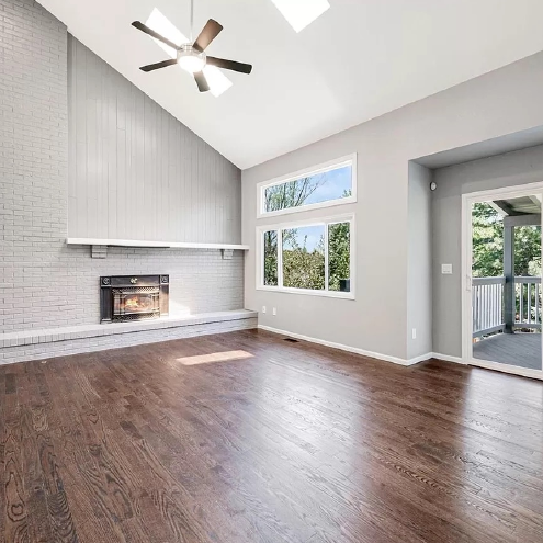 A living room with hardwood floors , a fireplace and a ceiling fan.