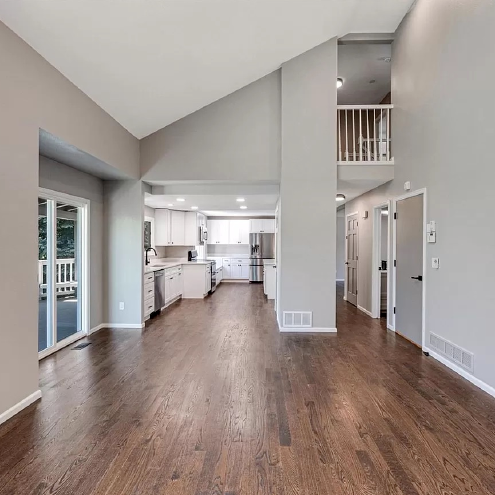 An empty house with a vaulted ceiling and hardwood floors