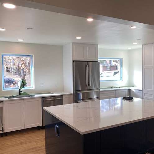 A kitchen with stainless steel appliances , white cabinets , and a large island.
