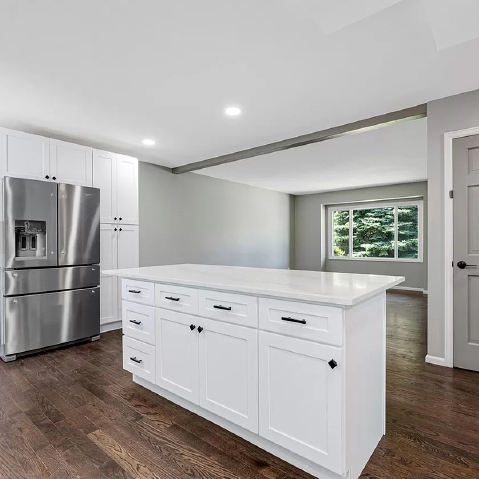 A kitchen with white cabinets , stainless steel appliances , and a large island.