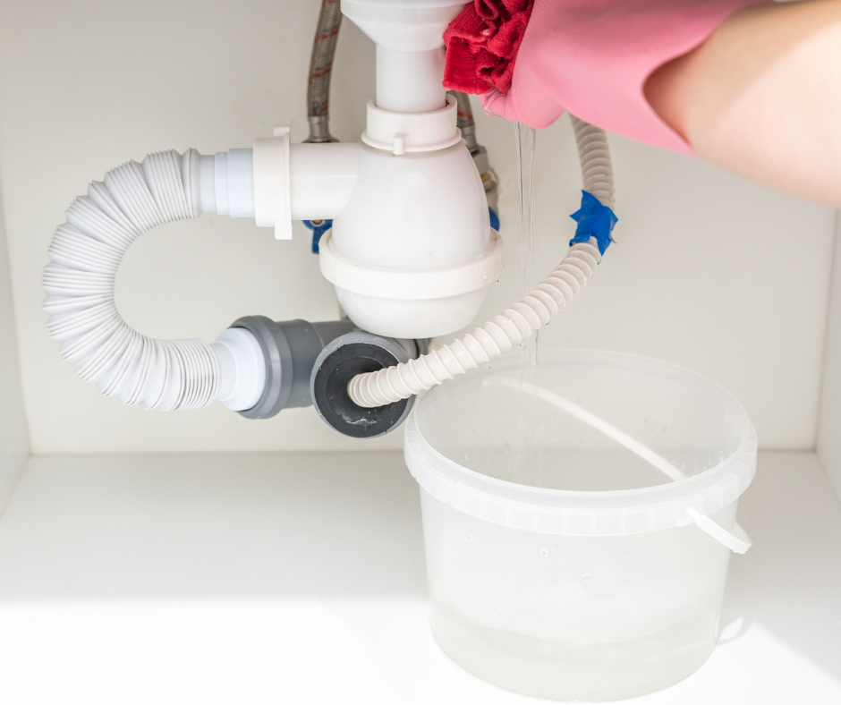 A man is fixing a sink in a kitchen with a plunger.