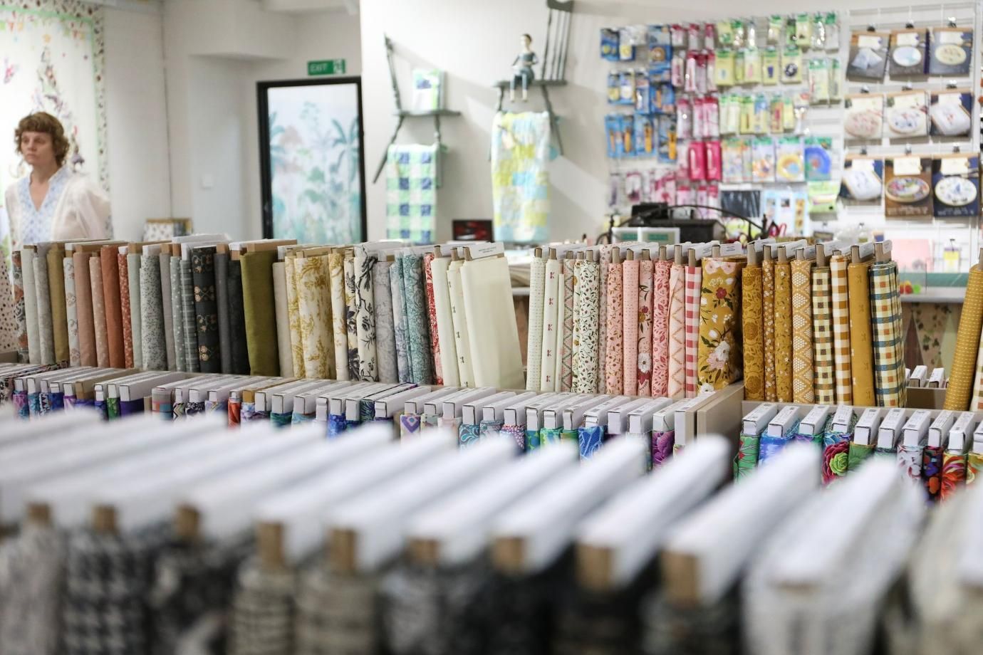 A Woman Is Standing in Front of A Display of Fabrics in A Store — Stitch 2340 In Tamworth, NSW