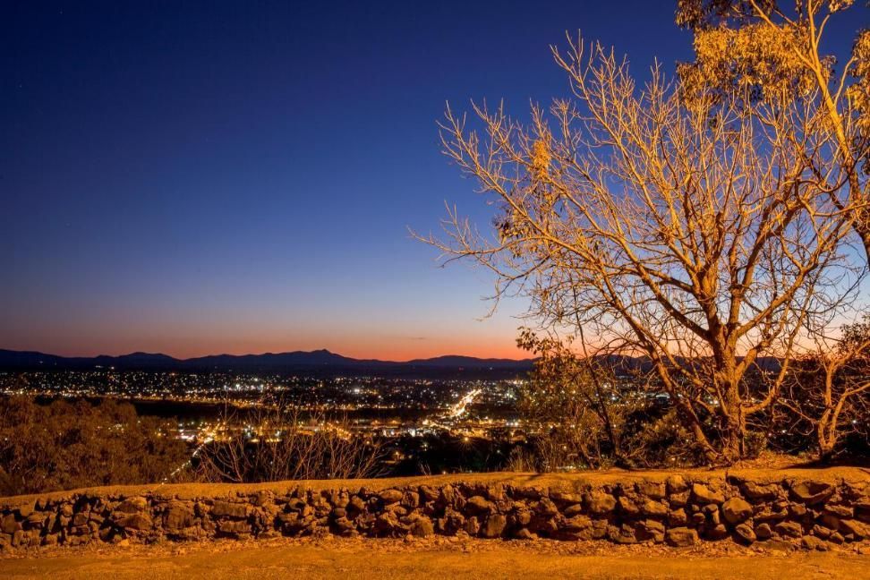 A Tree Stands in Front of a Stone Wall Overlooking a City at Sunset — Stitch 2340 In Manilla, NSW