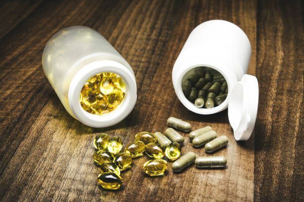 A bottle of vitamins and a bottle of pills on a wooden table — Monroe, LA — Coleman Chiropractic Clinic