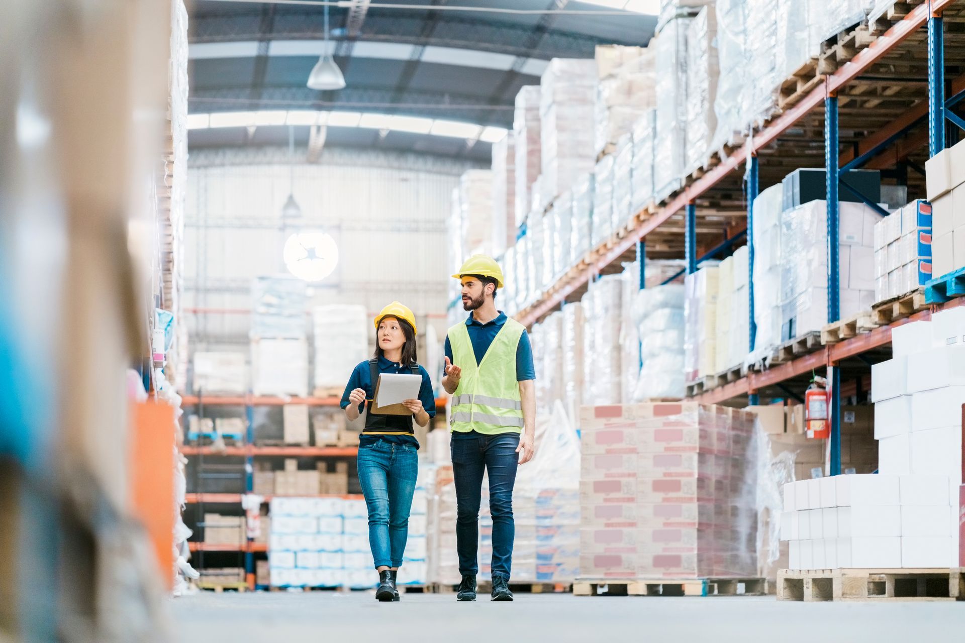 A man and a woman are walking through a warehouse.