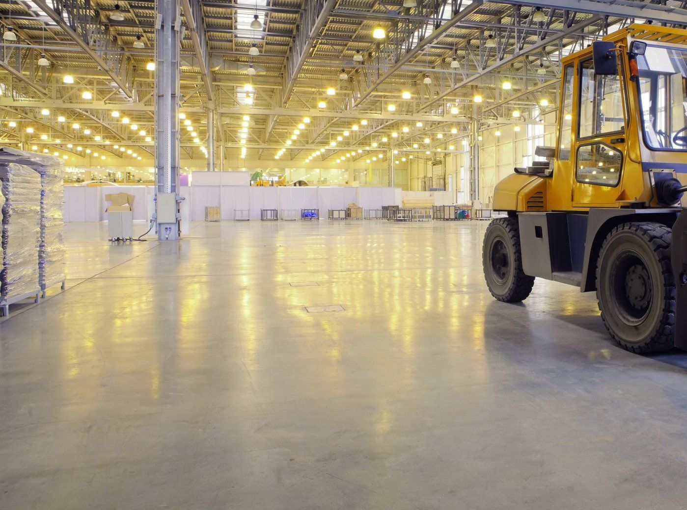 A yellow forklift is parked in an empty warehouse.