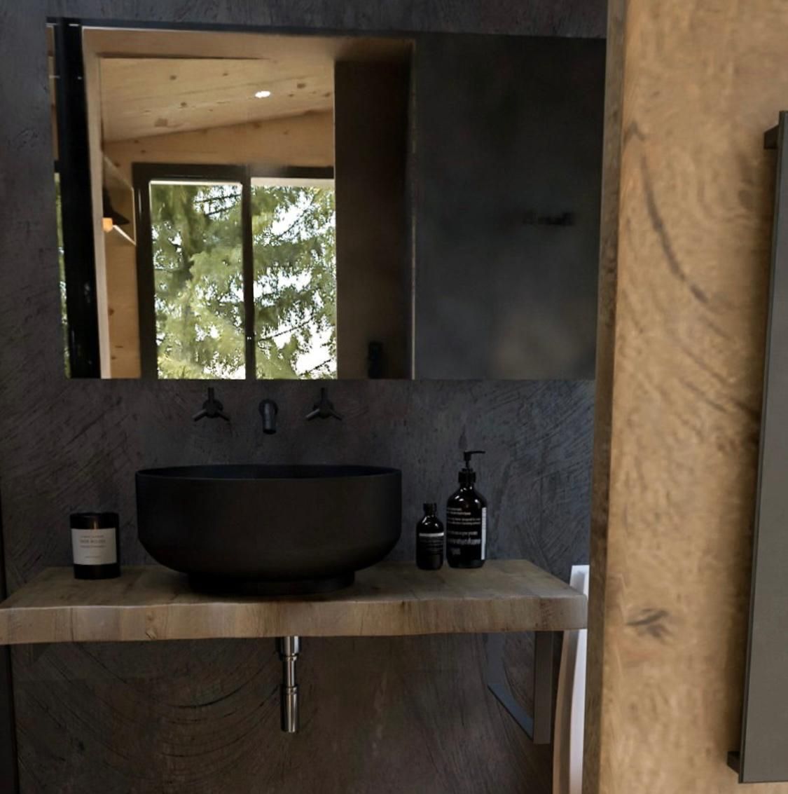 Modern bathroom with black bowl sink, wooden counter, and large mirror.
