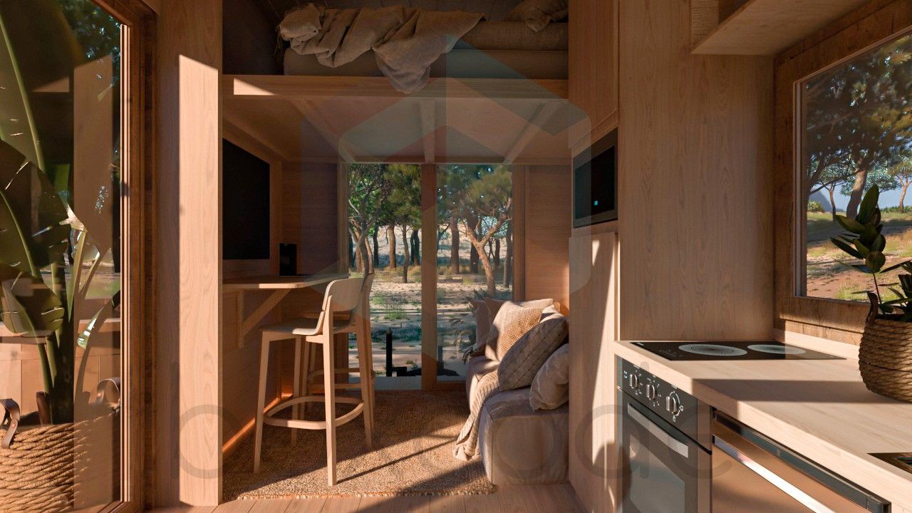 Interior of a small wooden cabin with a kitchen, seating area, and loft overlooking a sunny outdoor view.