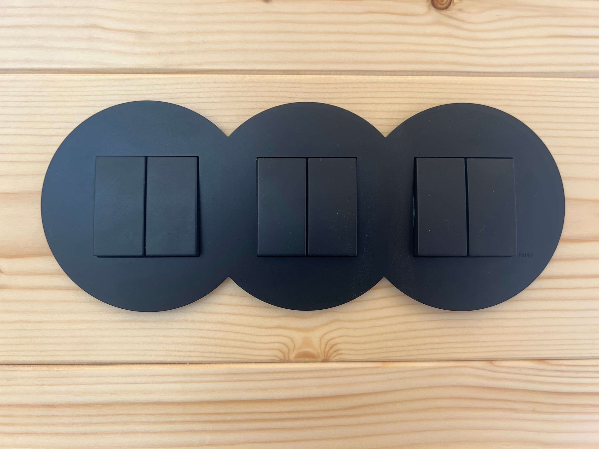 Black light switches on a wooden wall.