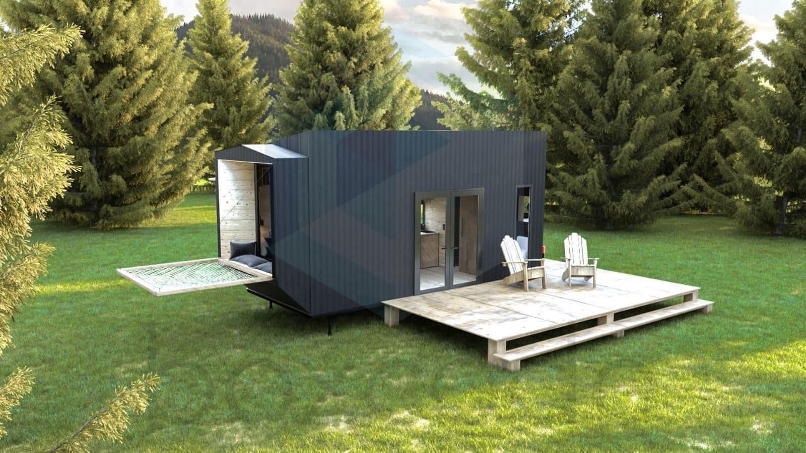 Modern, angular tiny home with deck and seating, set in a grassy area with trees and mountains in background.