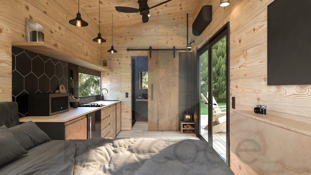 Cozy cabin interior with wood paneling, large bed, work area, and sliding door to outdoors.