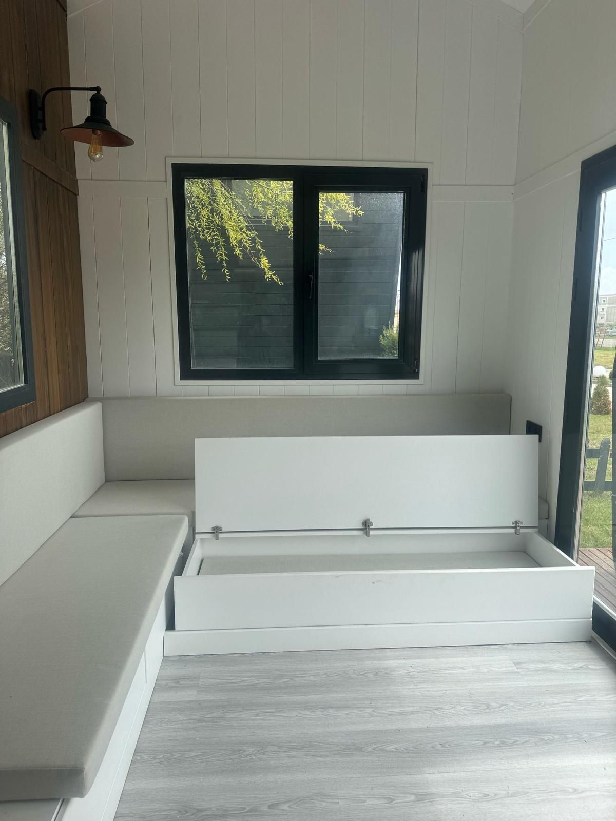 White interior with bench seating and storage. Window with view of greenery.