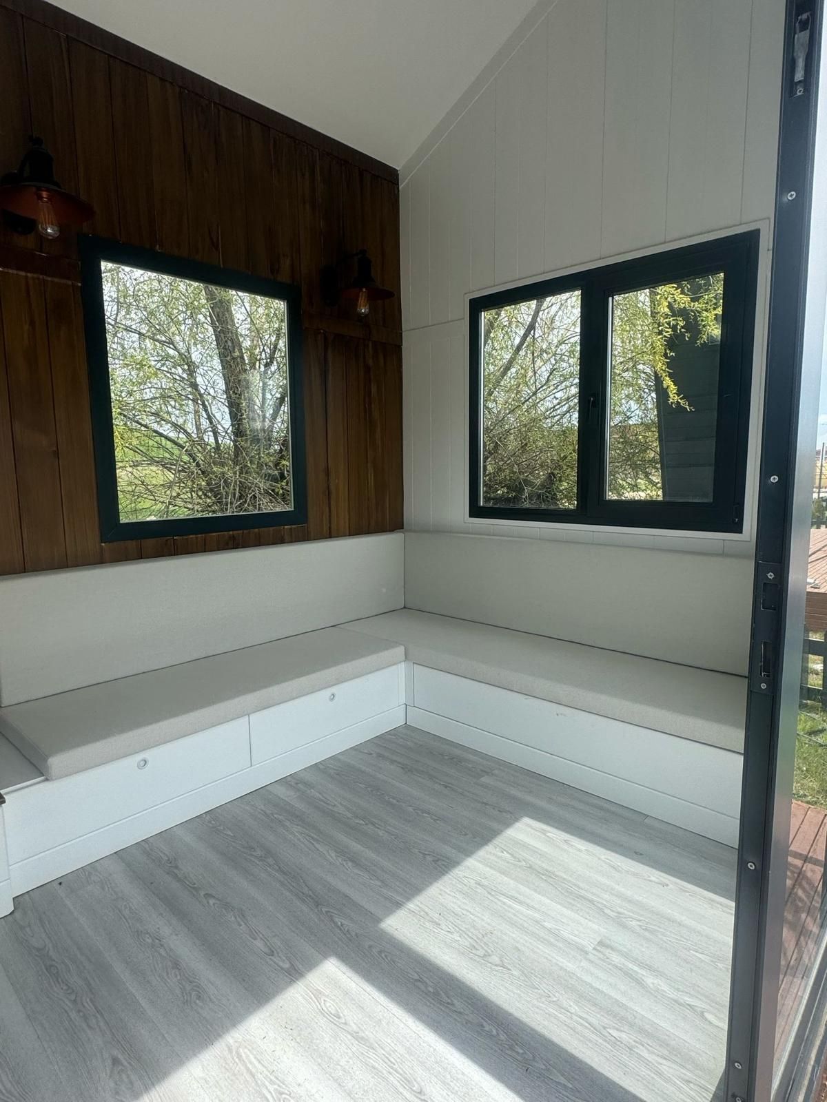 Cozy corner nook with built-in bench seating, windows, and light gray flooring.