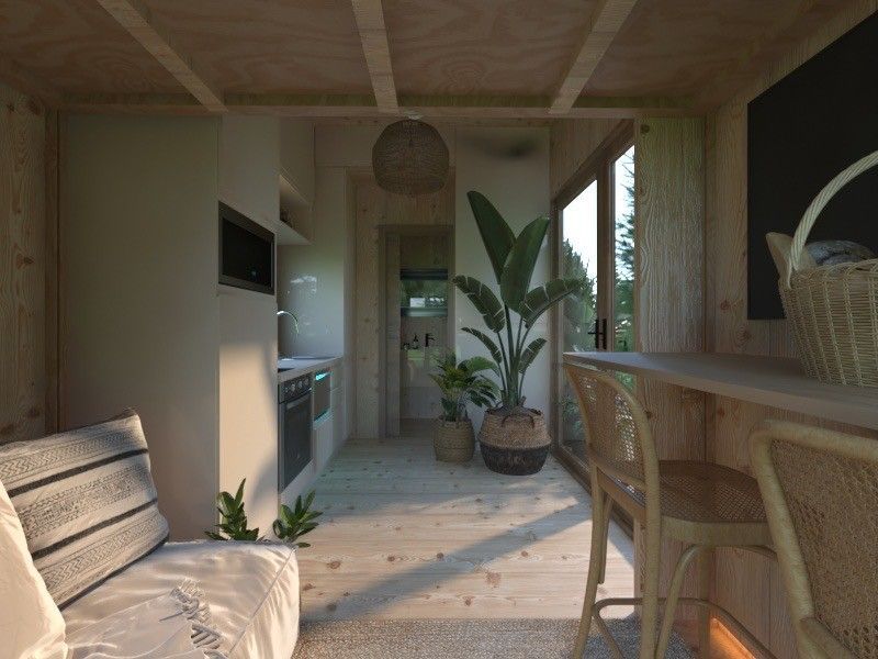 Interior of a tiny house. Kitchen, dining area, and a living space. Light wood construction with plants and large window.