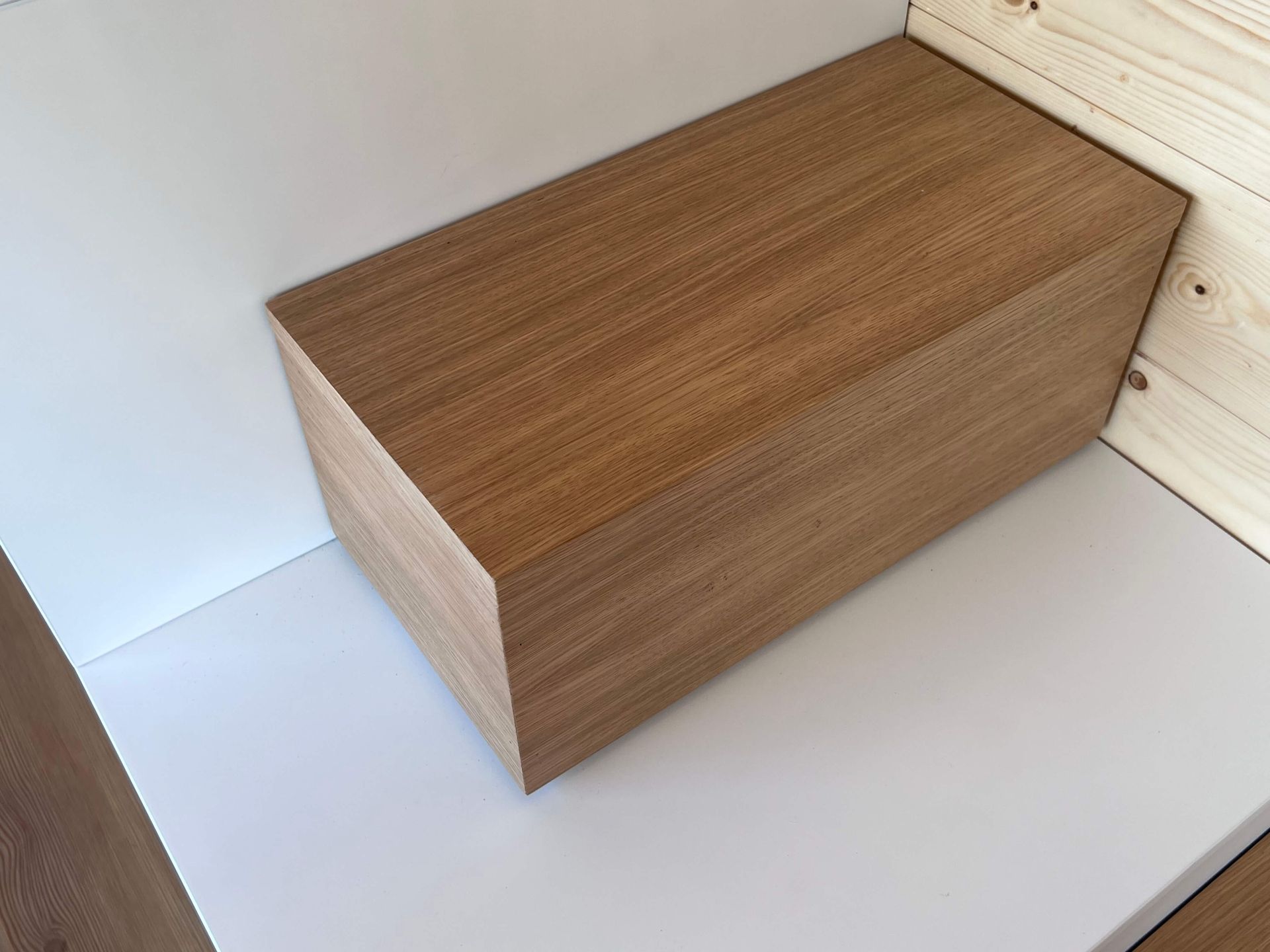 Wooden block resting on white surface, against a wood-paneled corner.