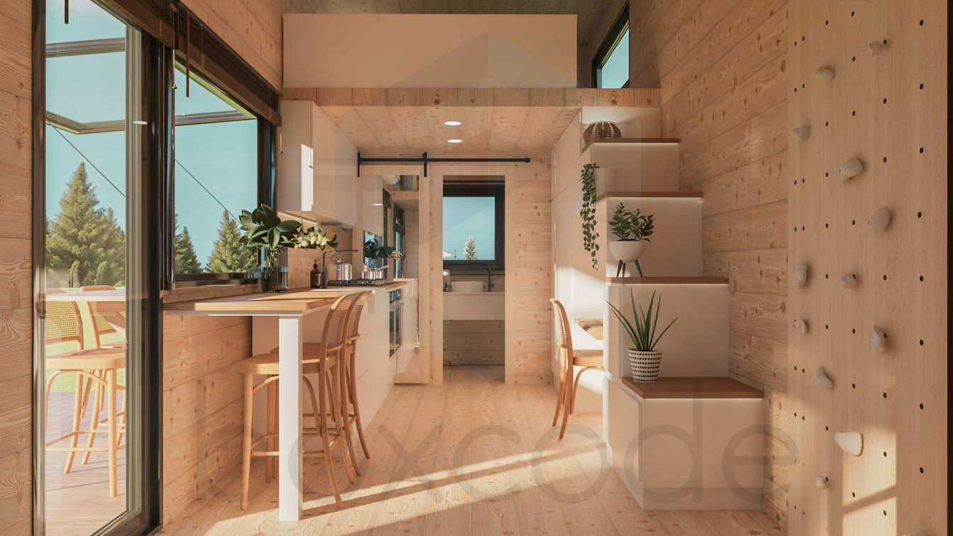 Interior of a tiny home with light wood paneling, kitchen, stairs to a loft, and large windows with a view.
