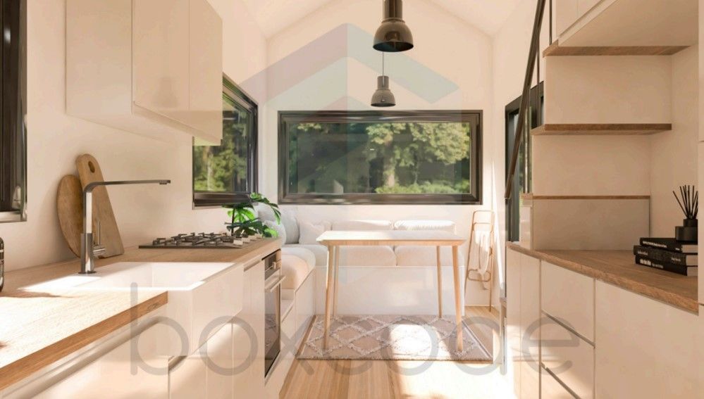 Interior of a tiny home kitchen with white cabinets, wooden counters, and a small dining nook.