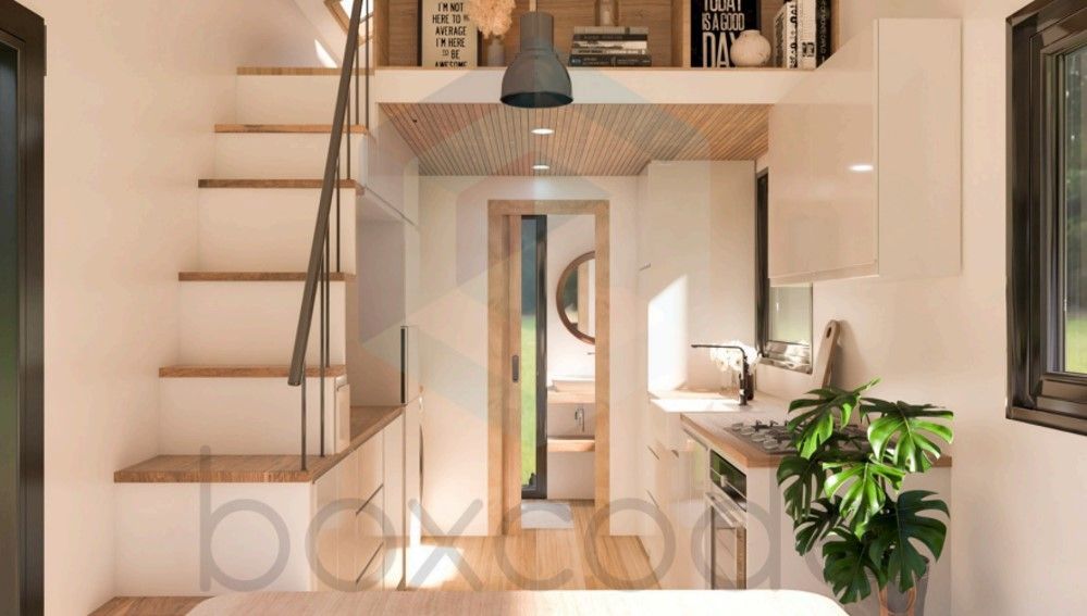 Interior of a tiny home with stairs, a kitchen, and a loft area with shelves.