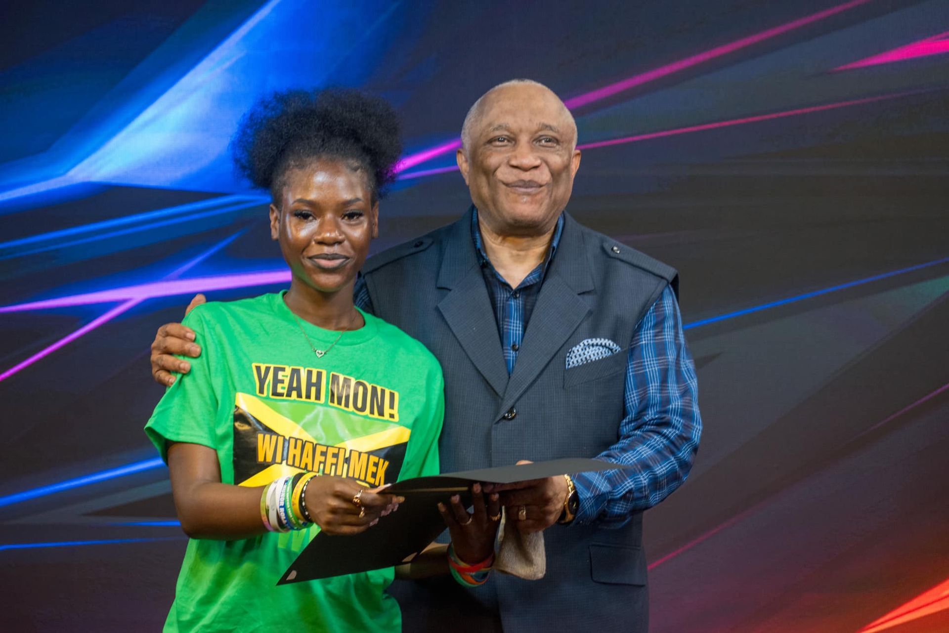 Young woman in green shirt and older man smiling holding certificate.