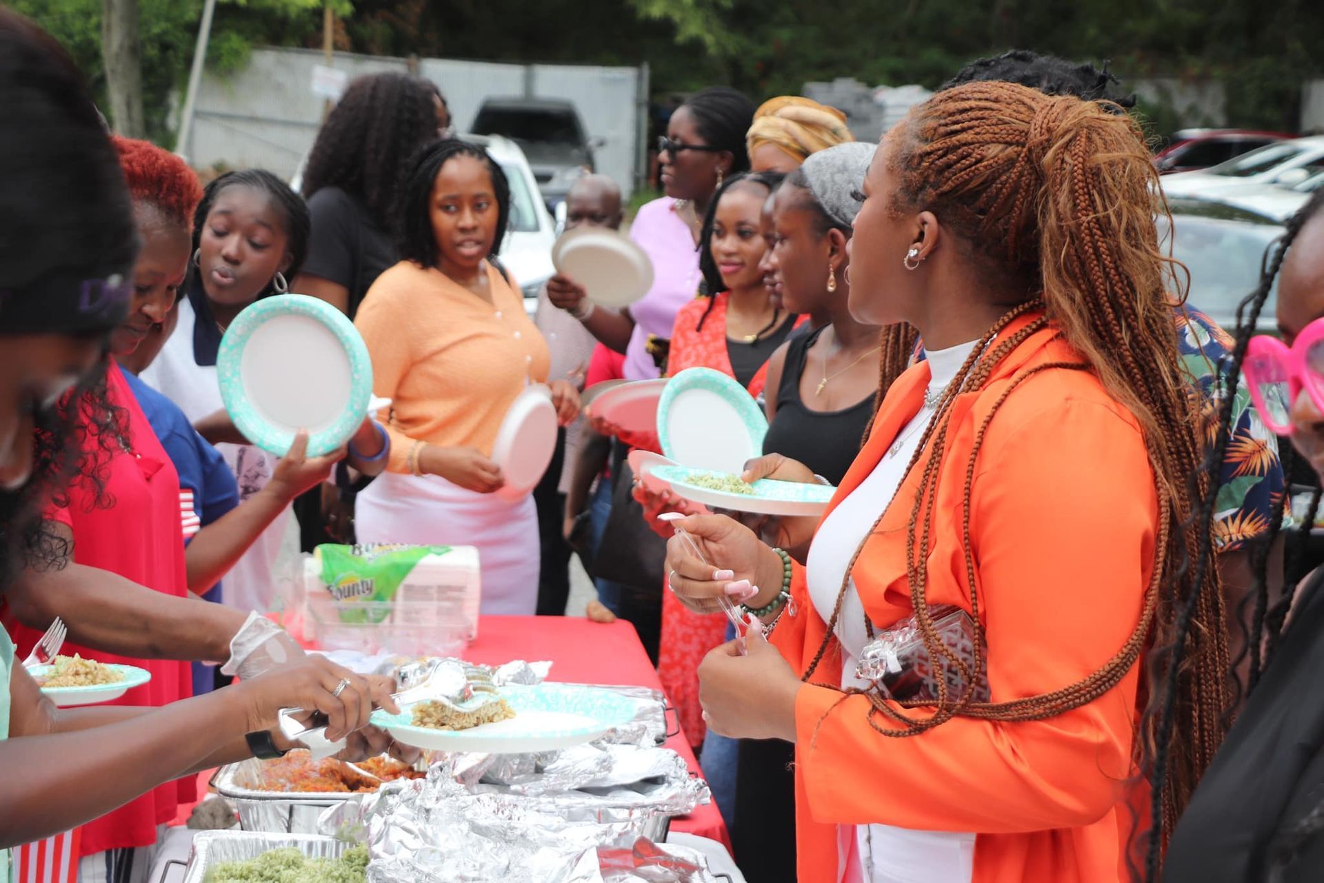 Group of women at an outdoor event, eating food from a buffet.