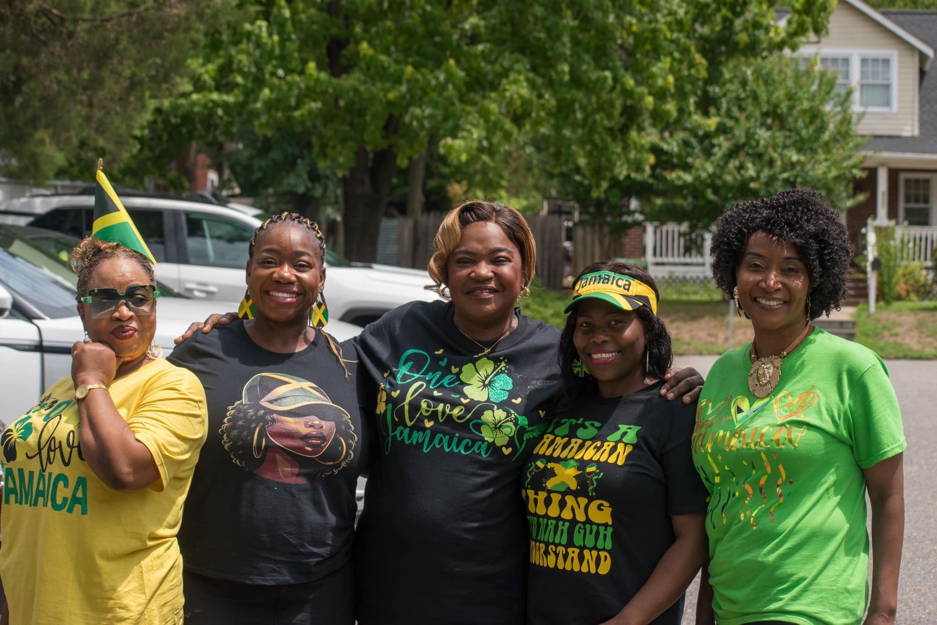 Five women in Jamaica-themed attire, smiling and posing outdoors.
