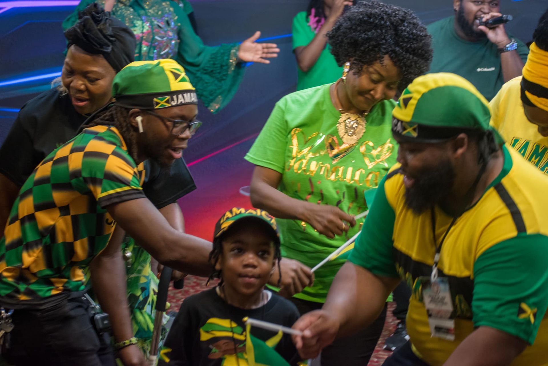People wearing green and yellow Jamaica apparel, celebrating, some holding flags.