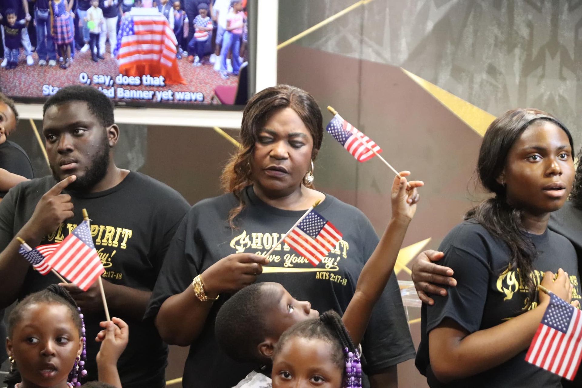 People holding small American flags; some looking upwards with serious expressions.