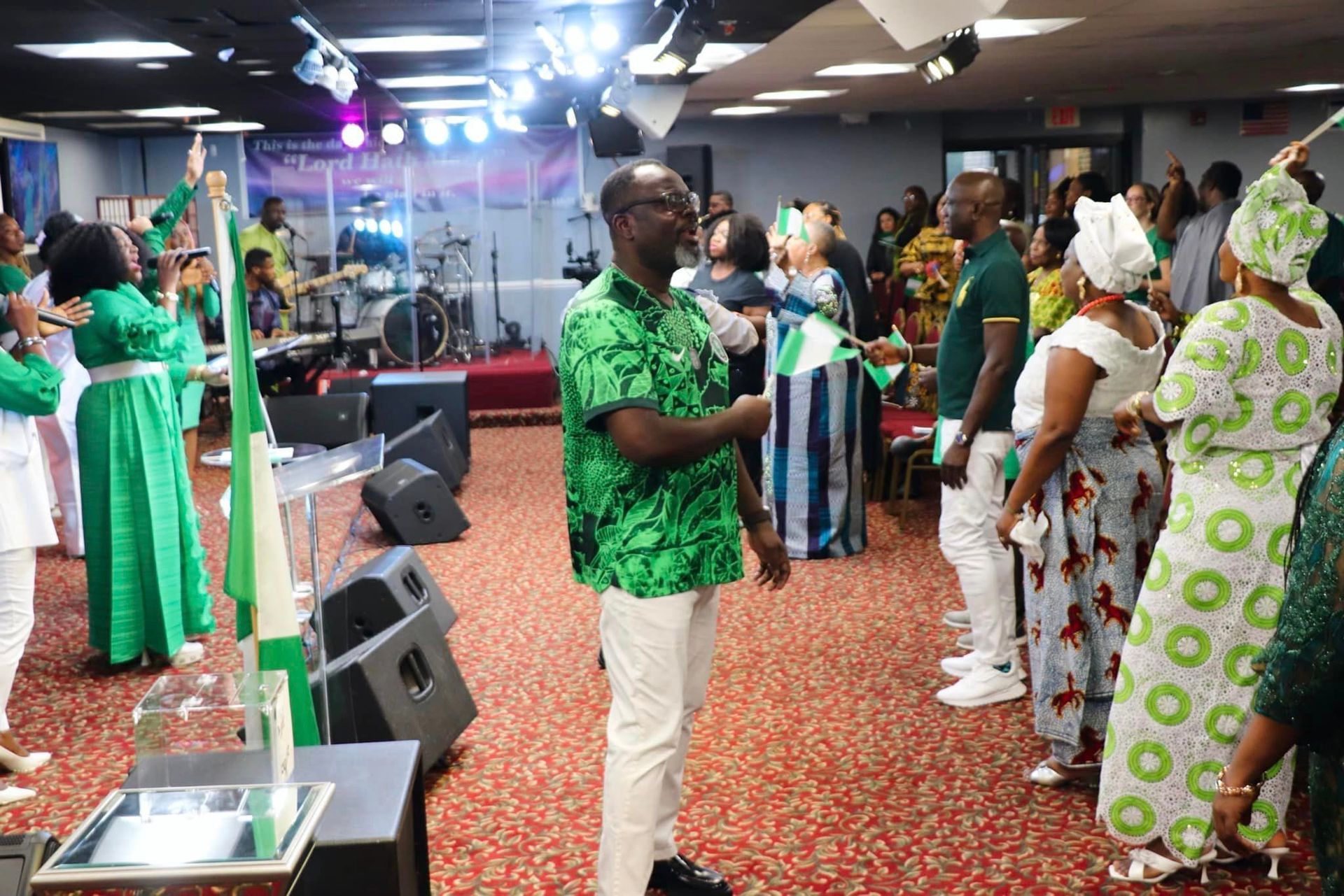 People in green and white attire wave Nigerian flags inside a church.