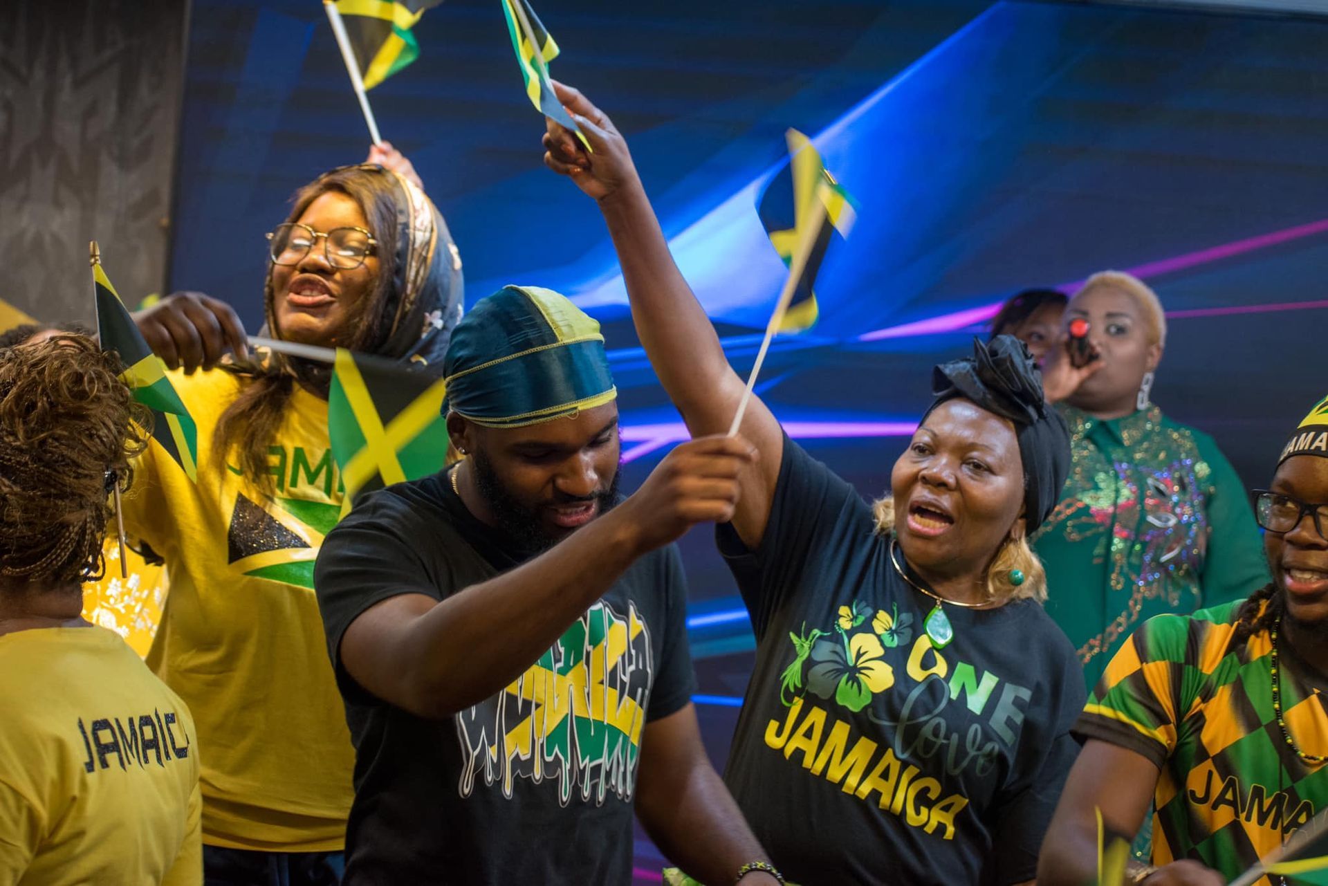 People in Jamaica gear celebrating with flags and raised arms.