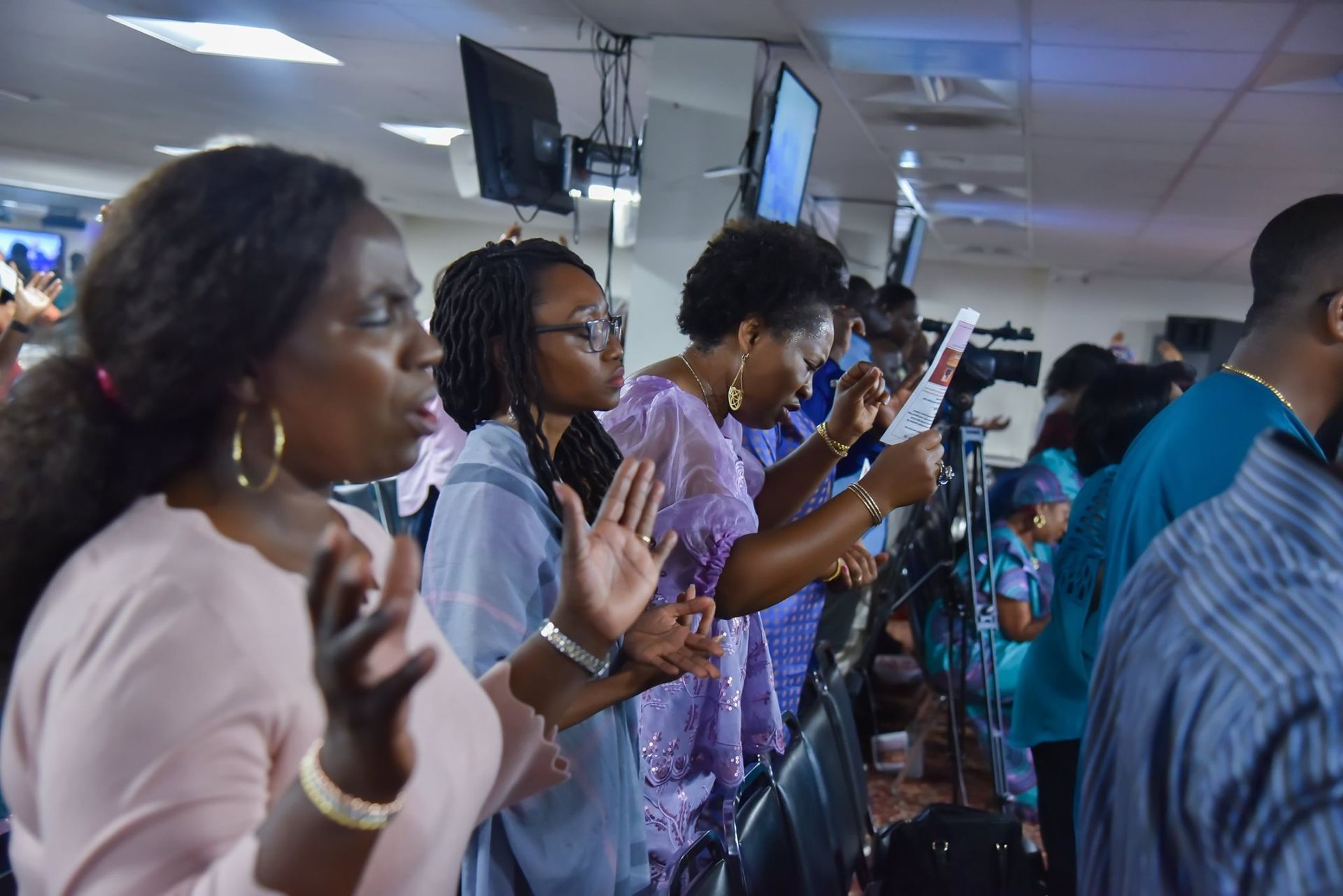 People singing and praying in a church, raising their hands.