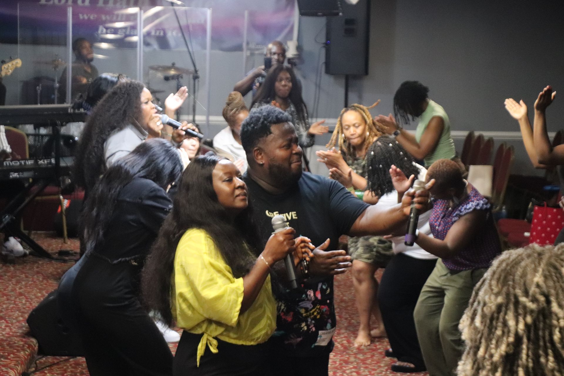 People singing and dancing at a church service. Black man and woman sing with microphones.