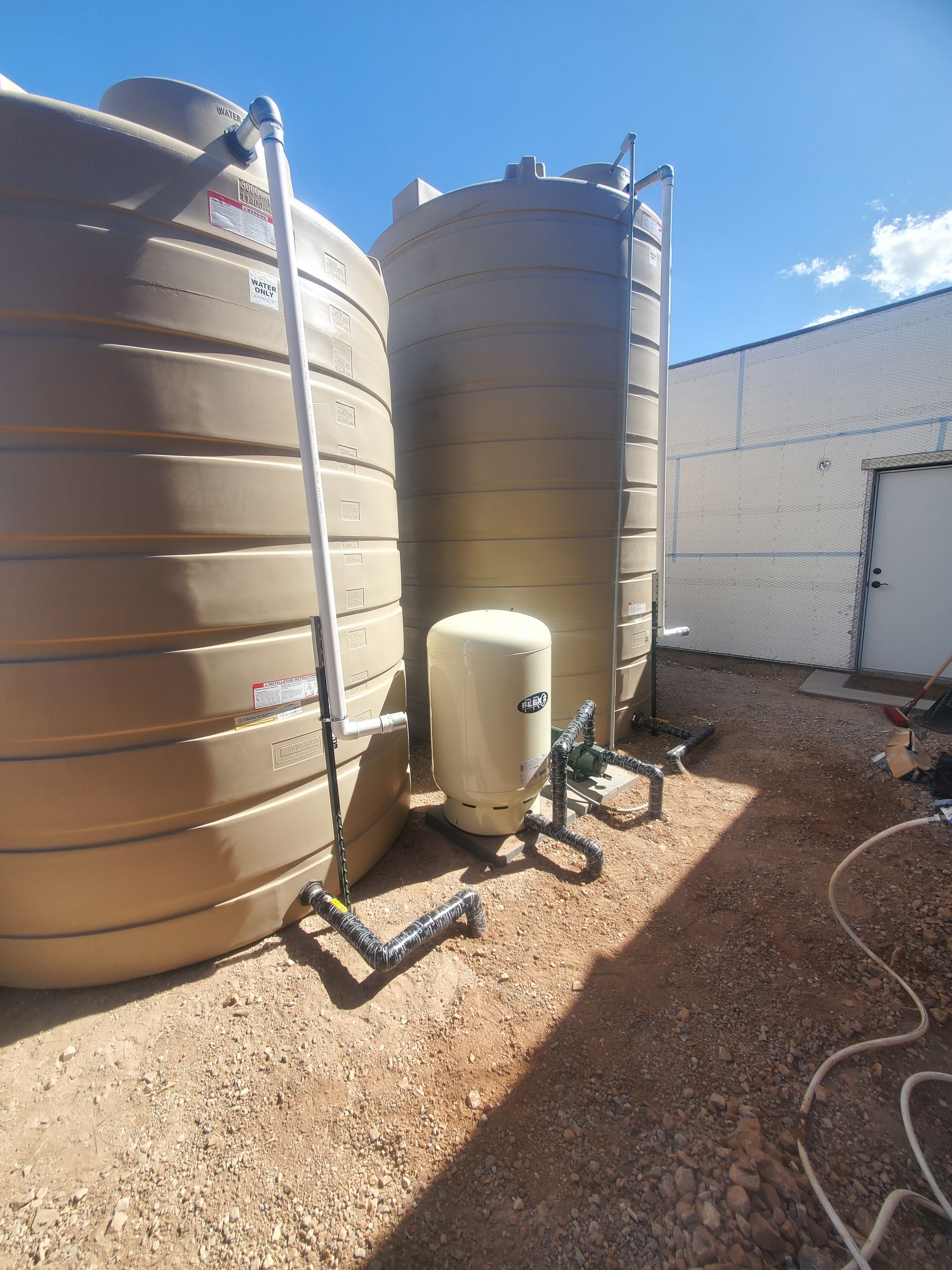 a couple of water tanks are sitting next to each other on top of a dirt field .