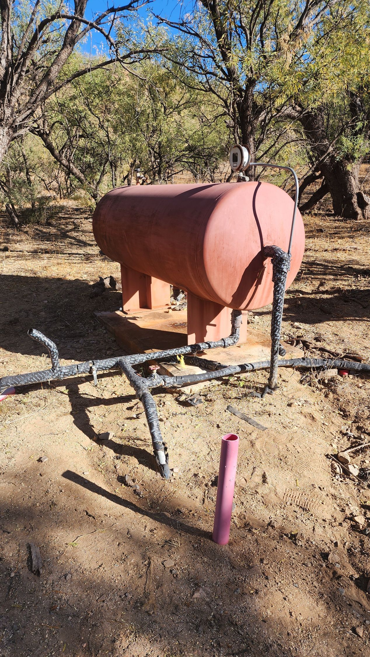 a large red tank is sitting in the middle of a dirt field .