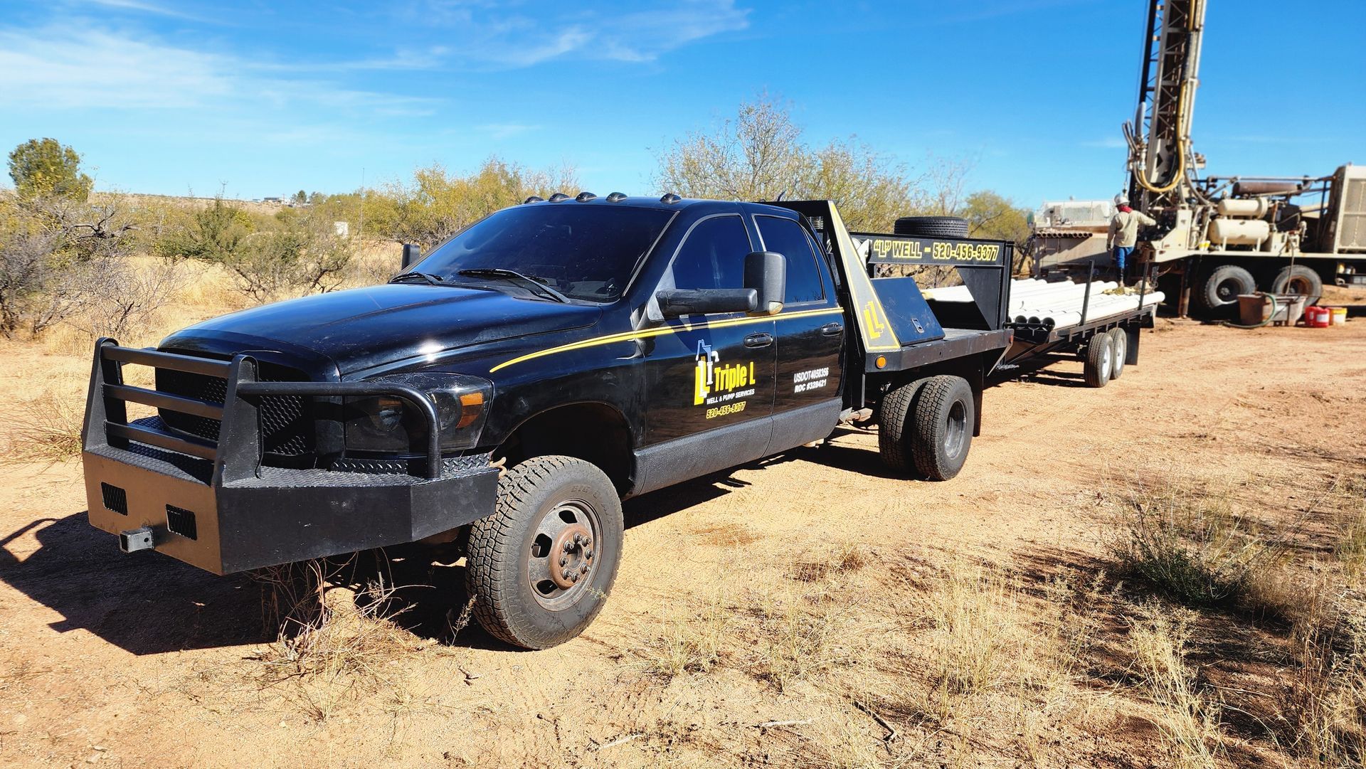 a black truck is parked in a dirt field next to a drilling rig .