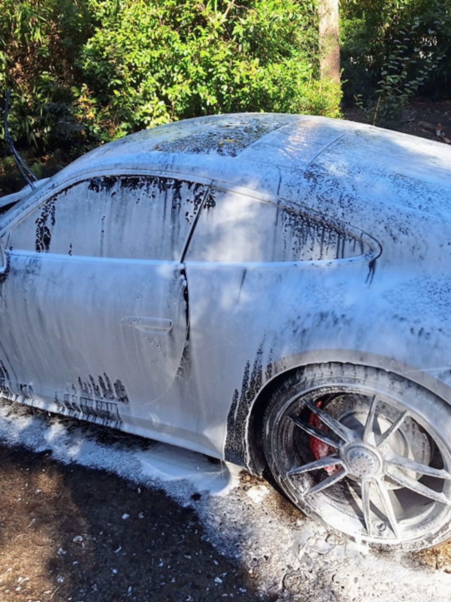 A car is covered in foam and is sitting on the ground.