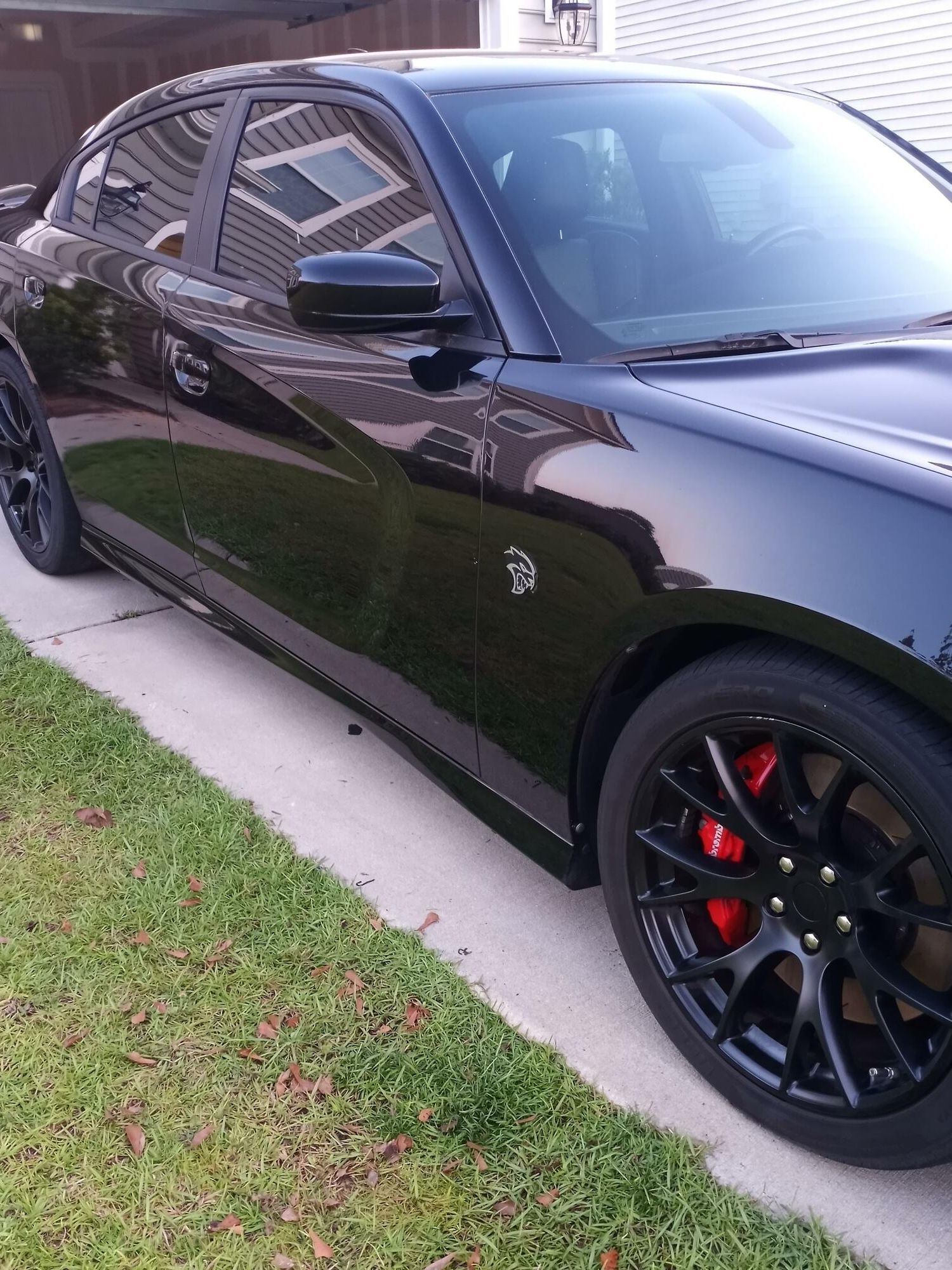 A black car with red brake calipers is parked on the side of the road
