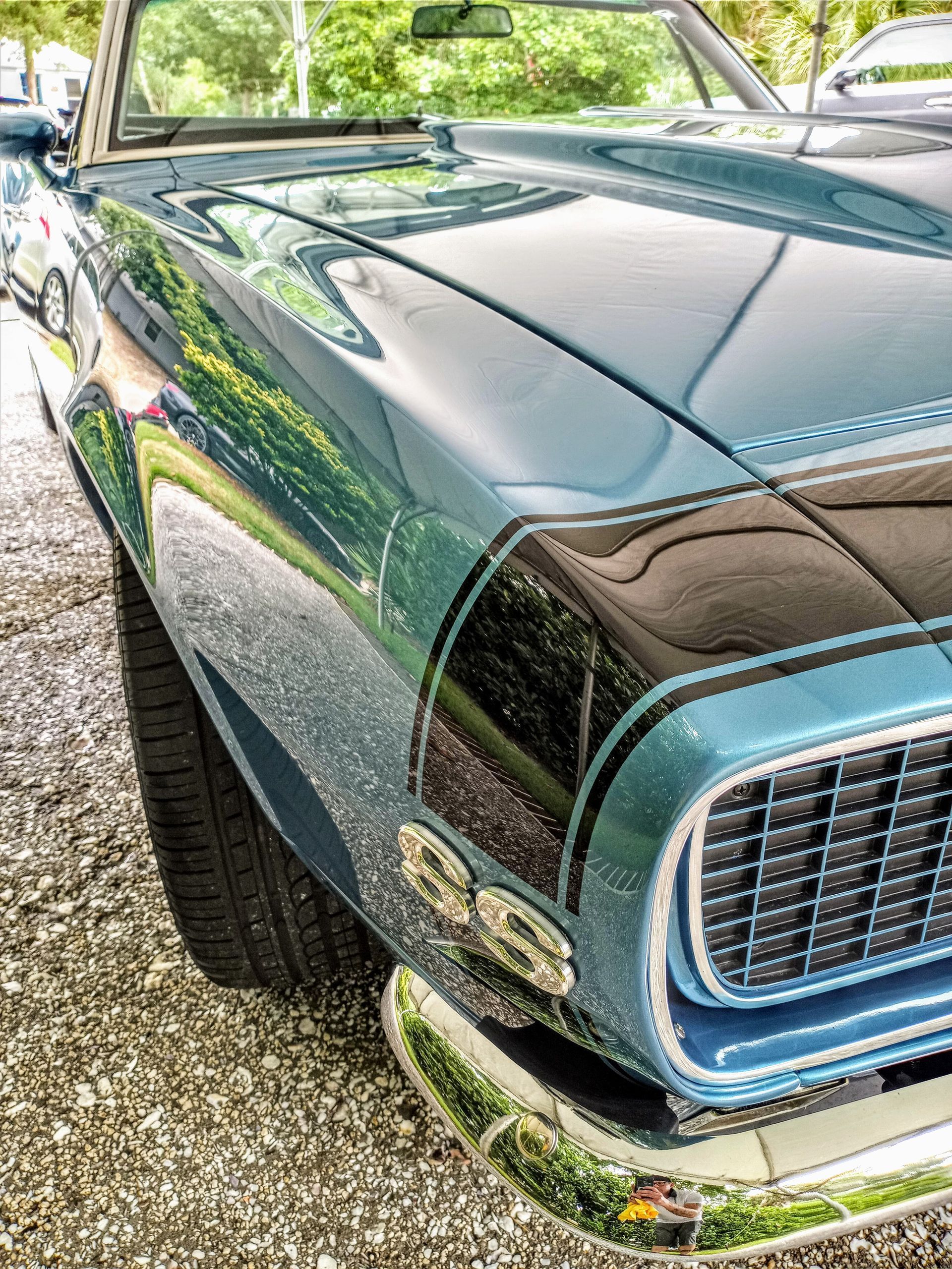 A close up of a blue car parked on gravel.