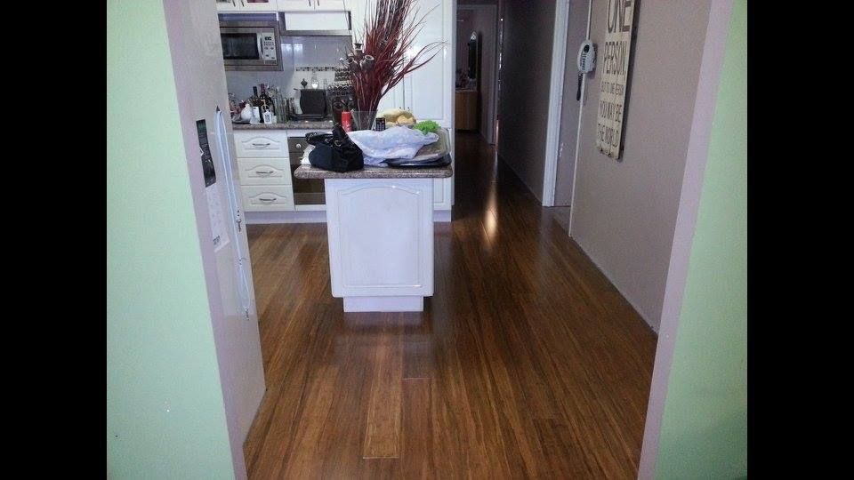 A Kitchen With a Wooden Floor and White Cabinets — Timberfection Queensland in Yatala, QLD